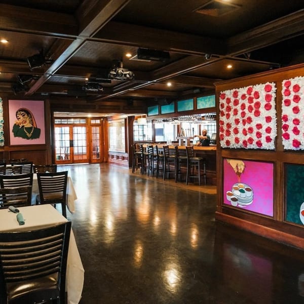 Curry Club's dining room with dark wood, Indian art, a bar, and set tables.