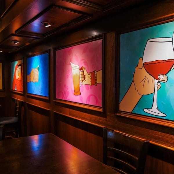 Curry Club's dining area with colorful pop art depicting hands holding drinks on the walls.