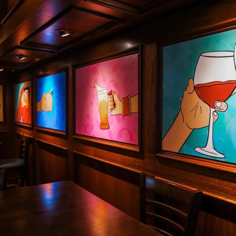 Curry Club's dining area with colorful pop art depicting hands holding drinks on the walls.