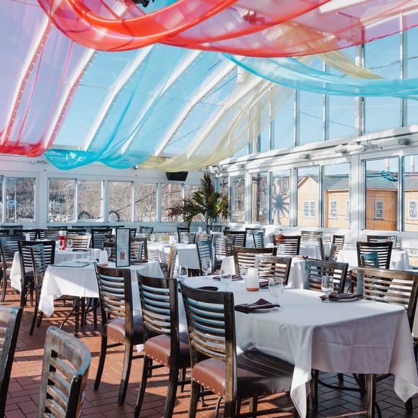 Curry Club's bright dining room with white-clothed tables, wooden chairs, and colorful ceiling drapes.