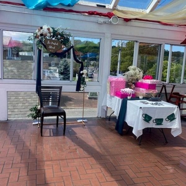 A decorated sunroom with a table of gifts, a chair, and a sign that reads "The Perfect Blend".