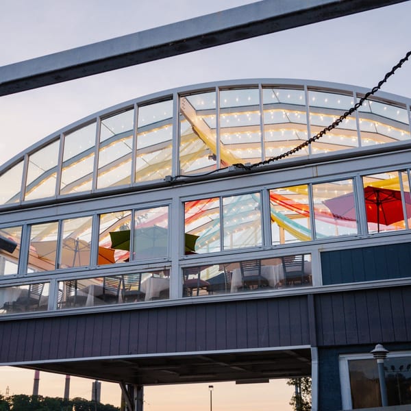 Curry Club's glass-enclosed dining area with colorful umbrellas, string lights, and tables set for guests.