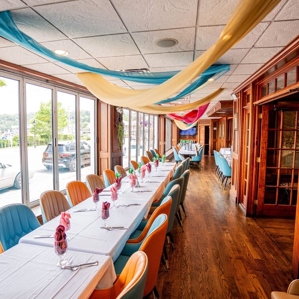 Long dining tables with colorful chairs and draped fabric decorations in the Curry Club restaurant.
