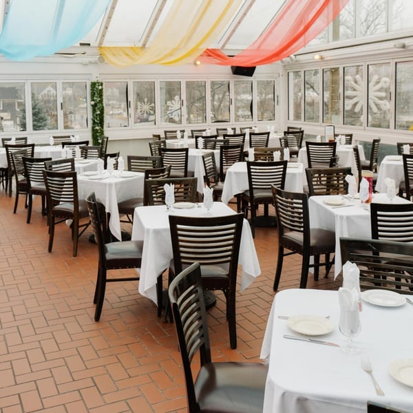 Curry Club's dining room with white-clothed tables, dark chairs, and colorful ceiling drapes.
