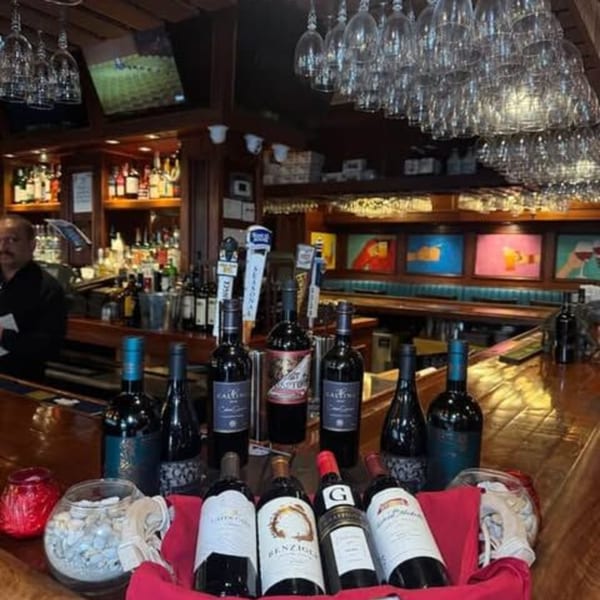 A well-stocked bar at Curry Club with wine bottles, beer taps, and hanging wine glasses.