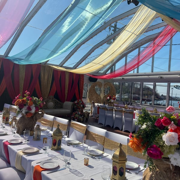An Indian-themed event space with colorful drapes, ornate decor, and elegantly set tables.
