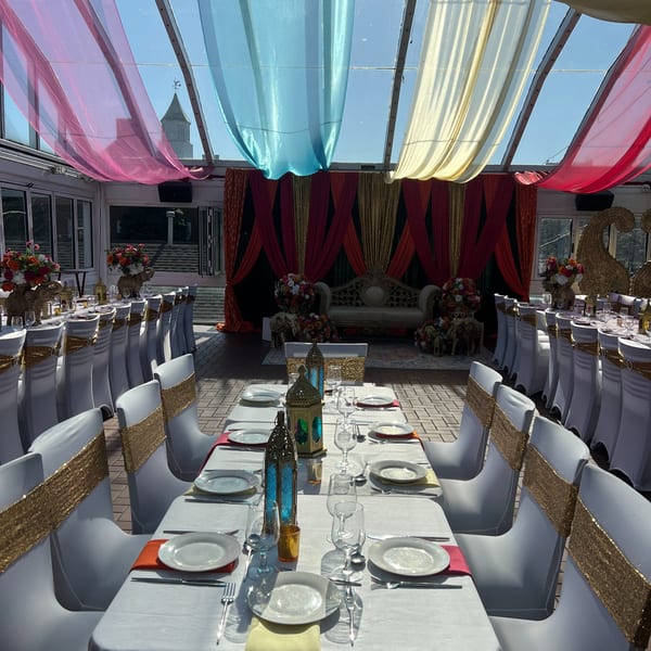 An Indian-themed event space with colorful drapes, decorated tables, and an ornate stage.