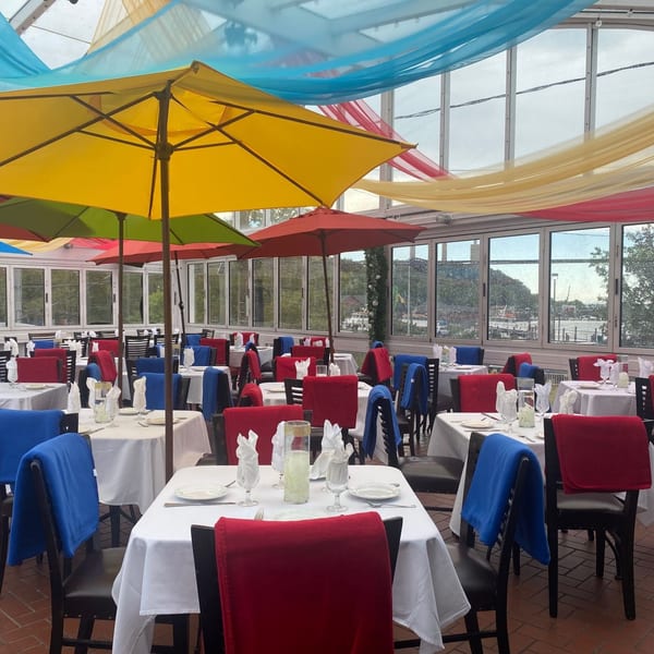 Curry Club's vibrant dining room with colorful umbrellas, red and blue chairs, and white-clothed tables.