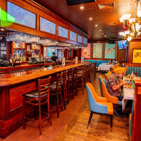 The Curry Club restaurant interior features a long wooden bar, bar stools, and dining tables with patrons.