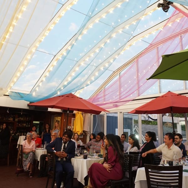 Guests seated at tables under a skylight with colorful drapes and string lights at Curry Club.