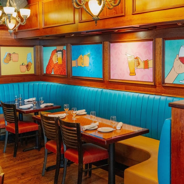 Curry Club dining room with vibrant blue booths, wooden tables, and colorful Indian-themed art.