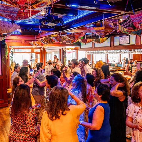 Guests dancing under colorful umbrellas and blue lights at Curry Club, an Indian restaurant.