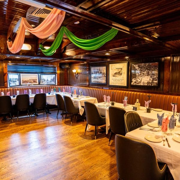 Curry Club's dining room with set tables, brown leather banquettes, and draped fabric on the ceiling.
