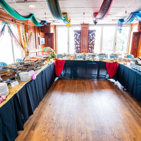 Curry Club's Indian buffet setup with chafing dishes, plates, and colorful ceiling drapes.
