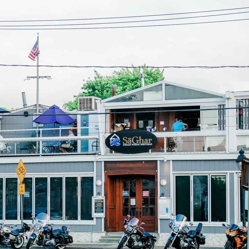 The Curry Club restaurant exterior with a large sign, outdoor seating, and motorcycles parked in front.