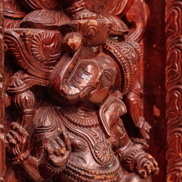 Intricately carved dark wood sculpture of the Hindu deity Ganesha, an elephant-headed figure.