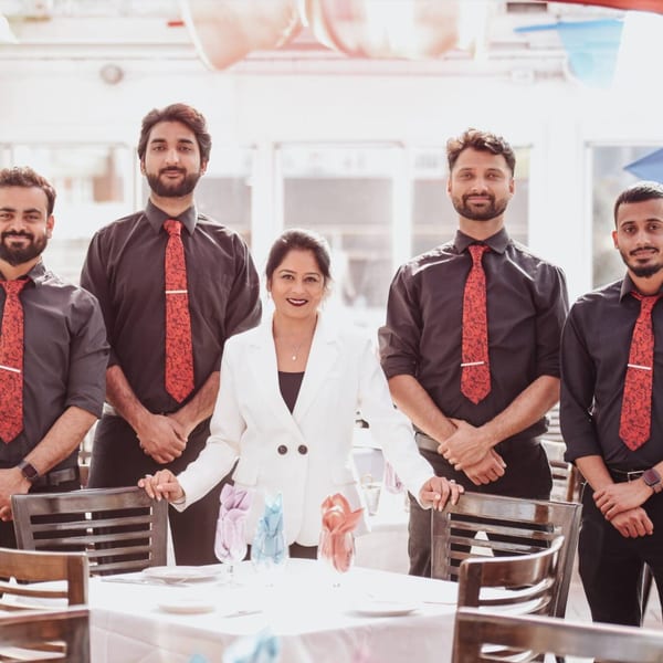 Curry Club staff, four men in black shirts and red ties, and one woman in a white blazer.