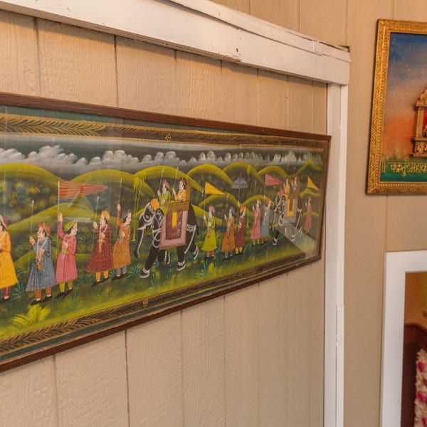 A framed Indian painting depicting a procession with elephants and people in traditional attire.