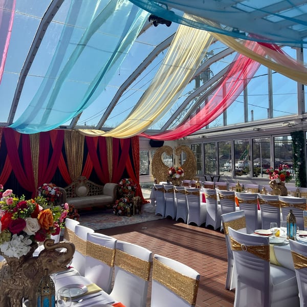 Curry Club's Indian-themed event space with colorful drapes, ornate seating, and elegantly set tables.