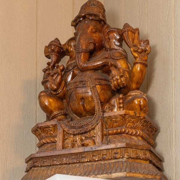 A detailed, carved wooden statue of the Hindu deity Ganesha, an elephant-headed figure, at Curry Club.