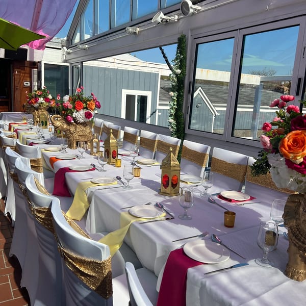 Long dining table set for a festive Indian event with colorful flowers, golden elephants, and lanterns.