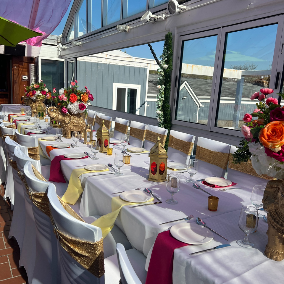 Long dining table set for a festive Indian event with colorful flowers, golden elephants, and lanterns.
