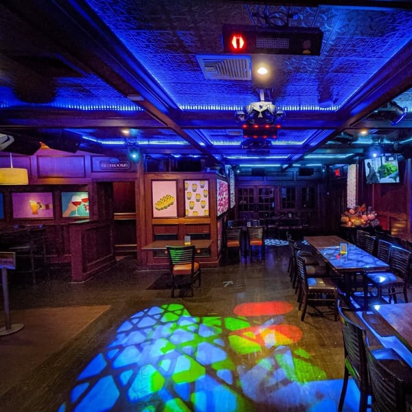 Curry Club's dimly lit dining area with blue lighting, patterned ceiling, and colorful floor projections.
